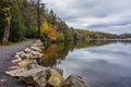 Clouds are reflected in a calm Minnewaska Lake in Orange County, NY, surrounded by bright fall foliage on a partly cloudy day Royalty Free Stock Photo