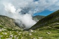 Clouds are rising above tarn near touristic path in mountains.