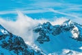 Clouds rolling over snowcapped mountain top in Julian Alps range during winter