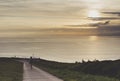 Clouds sky and sunlight sunset on horizon ocean. People on background seascape dramatic atmosphere rays sunrise. Relax view waves