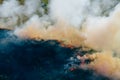 Clouds of smoke above dry burning field, natural disaster wildfire. Burning nature with fire, aerial view