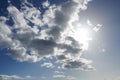 Clouds. Sun hiding behind clouds with blue sky. Beautiful sunshine from behind white and grey cumulus clouds at midday Royalty Free Stock Photo