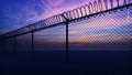 Clouds and a sunset can be seen through the metal prison fence with barbed wire. 3D Rendering Royalty Free Stock Photo