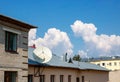 Clouds and a TV antenna. white satellite dish on the roof.