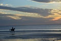 The clouds welcome the beach sunrise and the visitors walking and riding Royalty Free Stock Photo