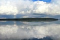 Clouds white on blue sky with a small rainbow with reflection in lake during the day in the natural environtent.