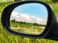 Cloudy blue sky landscape in a car rearview mirror Royalty Free Stock Photo