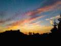 Cloudy colorful sunset over silhouettes of building and trees Royalty Free Stock Photo