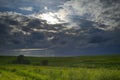 Cloudy day with a little sun shining over green fields Royalty Free Stock Photo