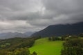 Cloudy day in Pyrenees mountains, France. Clouds over mountains with forest and bright green meadow. Awesome mountains landscape. Royalty Free Stock Photo