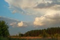 Cloudy evening summer sky over the forest valley of the reserved places of Russia. Landscape at sunset, field and grass.