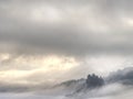 Cloudy hilly landscape. View over heavy cloud into rocky gulch