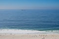 Cloudy horizon and Fog over the sea waves, natural background, red cargo ship on the horizon, beach in the foreground Royalty Free Stock Photo