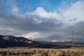 Cloudy November sky over snowy mountains and hills, electrical power lines, towers, desert Eastern Sierra Nevadas, California, USA Royalty Free Stock Photo