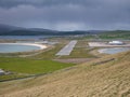 On a cloudy, overcast day, a view of Sumburgh Airport runway 15-33 between two beaches in the south of Shetland in the UK