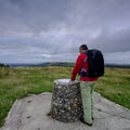 Cloudy overcast summer sunrise over the South Downs Way footpath from A middle aged male walker with backpack admiring the view