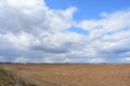 Cloudy sky in bright blue. Thick cloud. Agricultural field. A large ploughed field is boundless