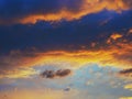 Cloudy sky at sunset. Dark blue and yellow natural background or wallpaper. The rays of the setting sun effectively illuminate the Royalty Free Stock Photo