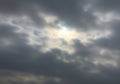 Cloudy sky with thick, gray clouds partially obscuring sunlight, creating a soft, diffused Royalty Free Stock Photo