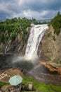 Cloudy summer day with insane view of beautiful and powerful Montmorency waterfall with a rainbow in front