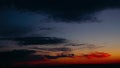 Dramatic clouds formatting storm in bright colors during sunset. Red, orange, purple sunset sky with clouds, fast motion