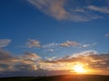 Cloudy sunset sky over a hill silhouette. Blue and orange color, Soft warm sun glow Royalty Free Stock Photo