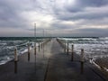 Cloudy weather, waves, sea and pier in the center.