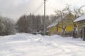 A cloudy winter day with snowfall. A street in a dacha village. Snow covered rural road and snowdrifts along the road near the Royalty Free Stock Photo