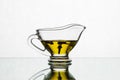 Clove oil in a glass sauceboat on a white background. Spice cloves in a gravy boat