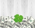 Clover leaf and dollars and white wood table, close-up