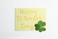Clover leaf and note with text HAPPY ST. PATRICK`S DAY on white table, flat lay Royalty Free Stock Photo