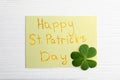 Clover leaf and note with text HAPPY ST. PATRICK`S DAY on wooden table, flat lay Royalty Free Stock Photo