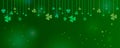 Clover shamrock leaves hung on strings on dark green background. Abstract St. Patrick`s day border horizontal panorama background