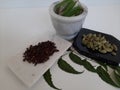 Cloves and Cardamom with mortar grinder on a plain white background