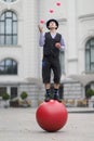 The clown and balancer juggles with pink balls