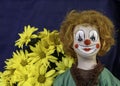Clown doll and yellow daisies on blue background Royalty Free Stock Photo