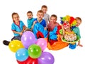 Clown holding cake on birthday with group children.