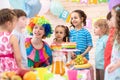 Clown playing with children. Kids group celebrate birthday at table. Holiday in a children`s club.
