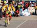 Clown riding unicycle in a public square