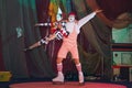 Clown in a striped t-shirt and rollers on his feet, holding a little girl in the form of harlequin, arms outstretched in greeting. Royalty Free Stock Photo