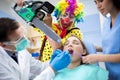 Clown threaten girl with chainsaw in dental ambulant Royalty Free Stock Photo