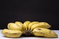 Clsoeup shot of a bunch of ripe yellow bananas on a white surface with a black background