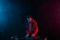 Club DJ mixing vinyl records with sound mixer on a party in night club. Young adult male person performing as a disc jockey Royalty Free Stock Photo