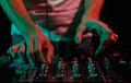 Club DJ playing music with sound mixer. Rave party disc jockey mixing musical tracks in close up