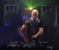 Club DJ with white headphones playing mixing music on turntable and dancing at party. Loudspeakers and lasers on background. slow Royalty Free Stock Photo