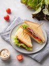 Club sandwich on a blue plate and napkin of ham cheese, cucumber, tomato and lettuce leaves close-up on a blue background with Royalty Free Stock Photo