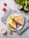 Club sandwich on a blue plate and napkin of ham cheese, cucumber, tomato and lettuce leaves close-up on a blue background with Royalty Free Stock Photo
