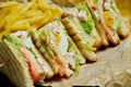 Club Sandwich with ham, tomatoes, pickled cucumber, egg, cheese and lettuce on a wooden tray. Close up. Tasty fast food. Colored Royalty Free Stock Photo