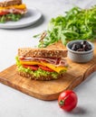 Club sandwich on a plate of bacon, cheese, tomato and lettuce on a wooden board