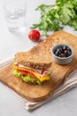 Club sandwich on a plate of bacon, cheese, tomato and lettuce on a wooden board